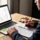 Person analyzing SEO data on a laptop with notes and coffee, emphasizing long tail keywords in SEO strategy