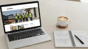 Laptop showing a contractor landing page with a notepad and coffee on a desk