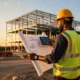Construction company foreman reviewing blueprints at a steel-frame build site